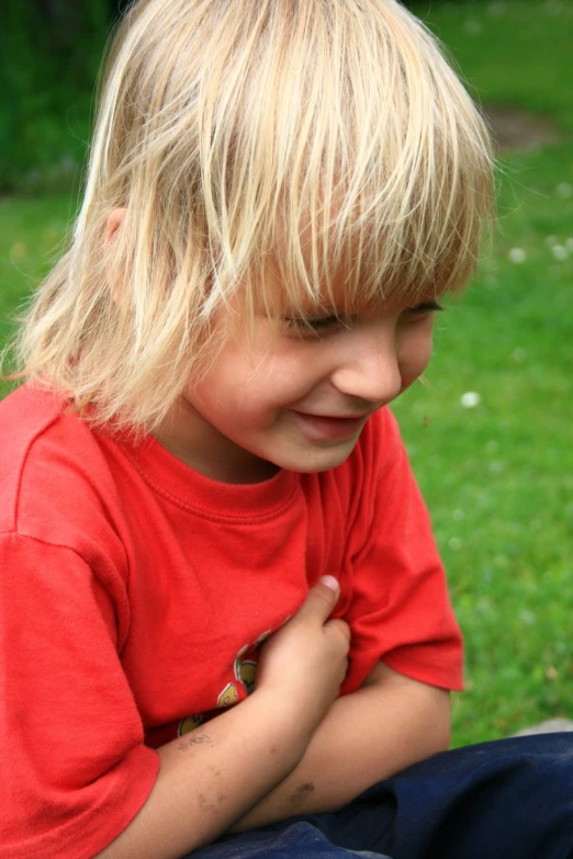 a boy wearing a red shirt and blue jeans