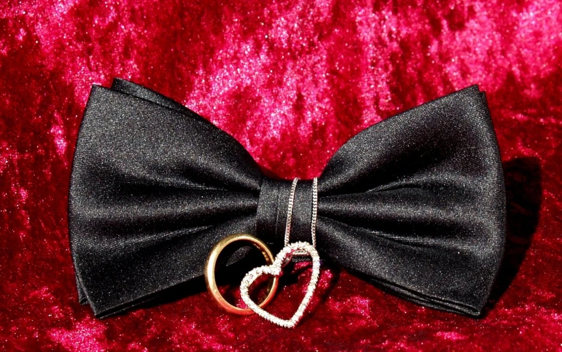 a black bow tie with a heart pinhole