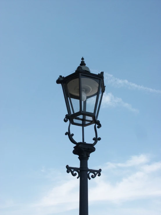 a lamp post with an airplane in the sky