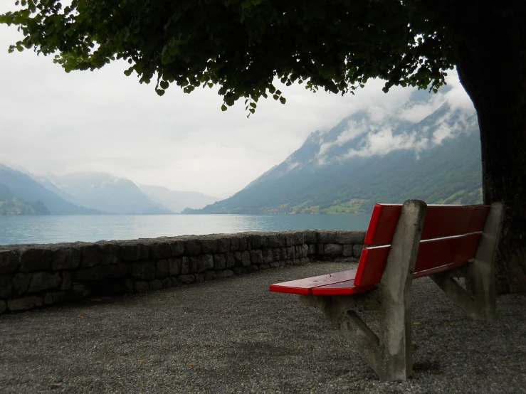 a bench is by a wall with mountains in the background