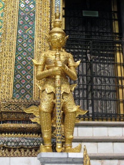 a statue of a man in gold stands on a marble step