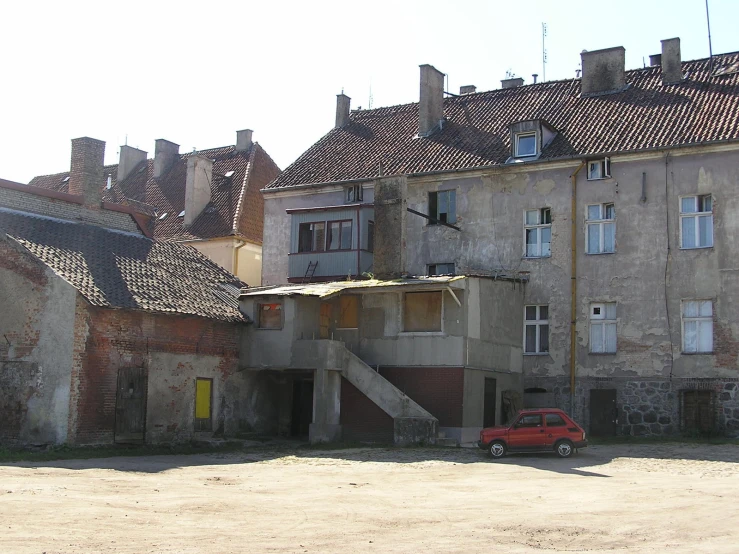 a red car parked in front of old buildings