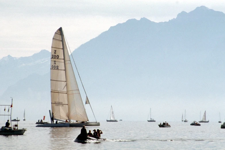 some sailboats are on the water and hills are in the background