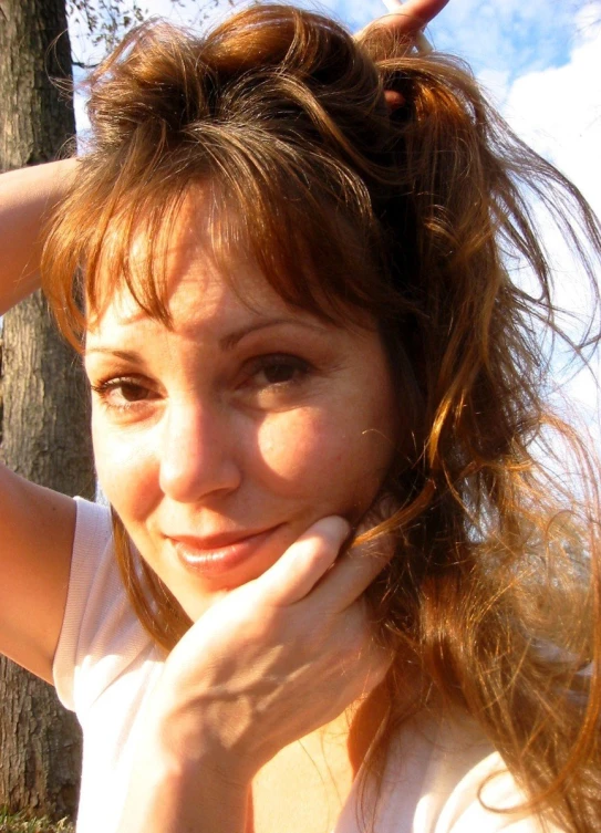 a woman looking at the camera while touching her hair