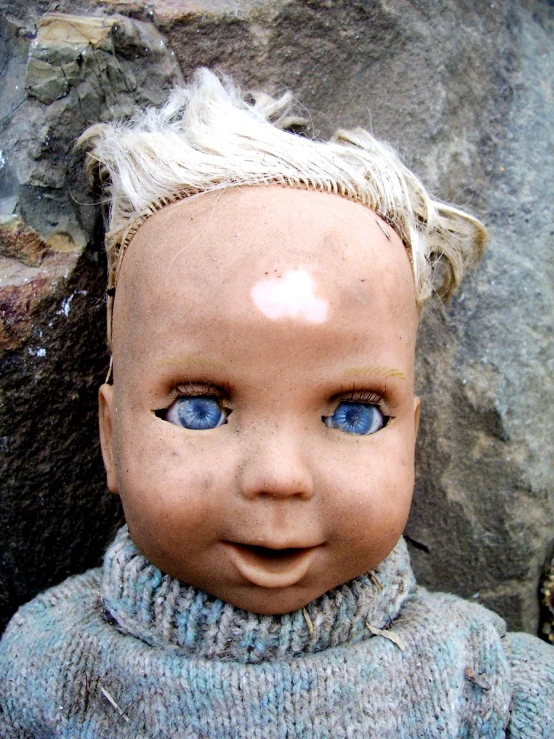 an antique baby doll wearing a blue sweater