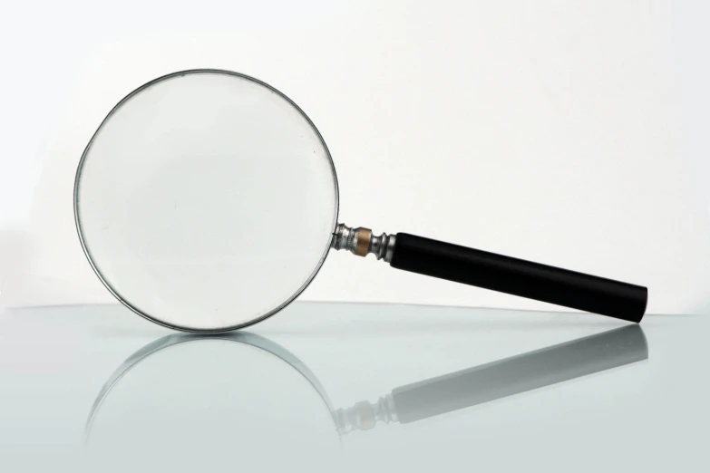 a black handled magnifying glass on a white surface