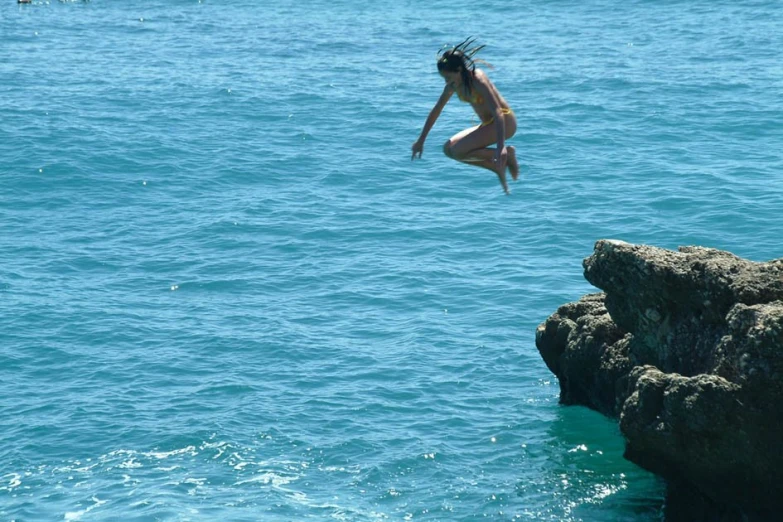 a person is jumping into the water off a cliff