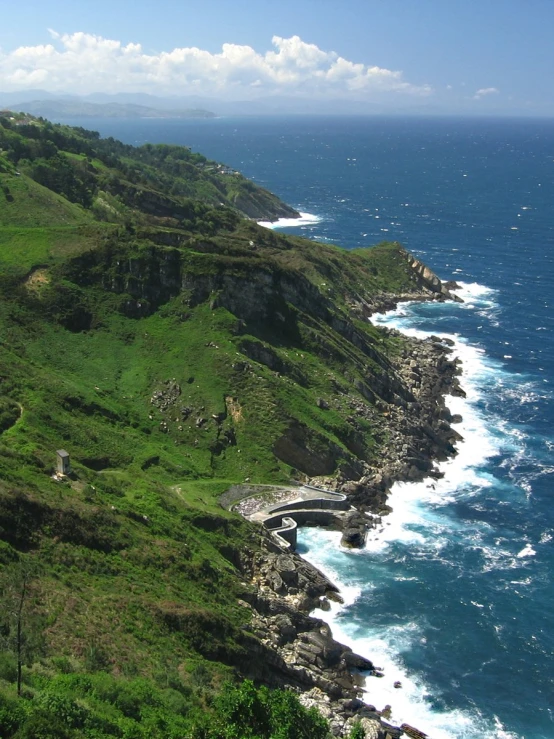 some rocky cliffs some water and green grass