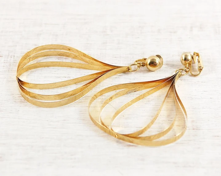 two toned gold earrings sitting on top of a wooden table