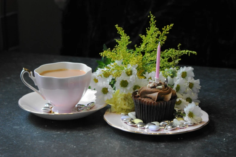 a cupcake on a saucer next to a white plate with flowers