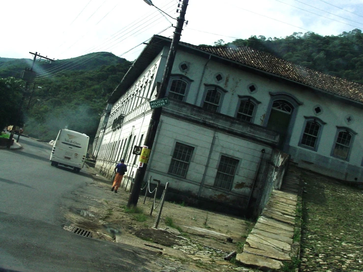 an old white house sits in front of a mountain