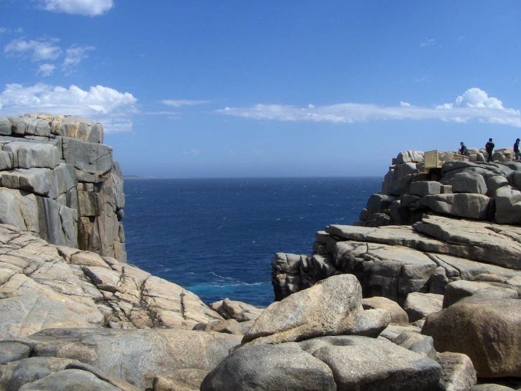 some people standing on rocks overlooking the ocean