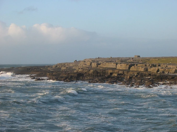 a large cliff with an ocean in the background