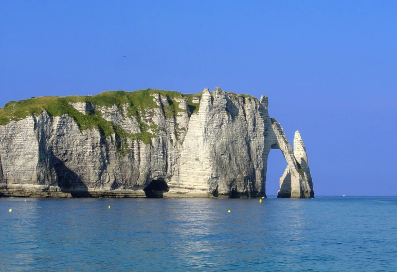 a rock formation sits in the middle of the ocean