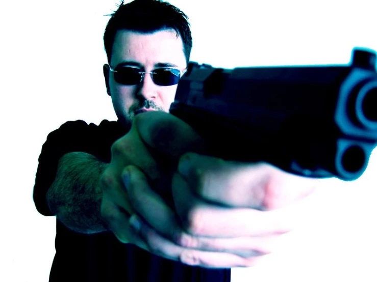 a man with sunglasses on holding a small gun