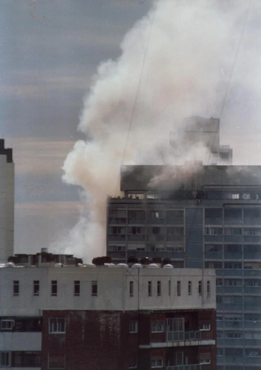 a building on fire in the distance while smoke rises up into the sky