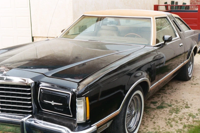 a large black car parked next to a garage