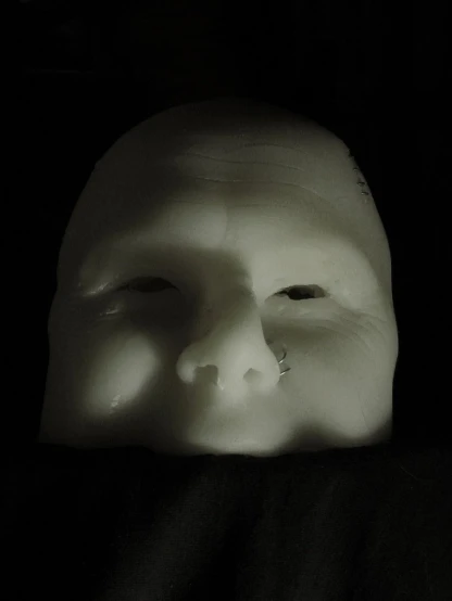 an unfinished mask casting a shadow on the dark background