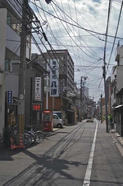 a street lined with buildings and wires, with bikes parked along the sides of it