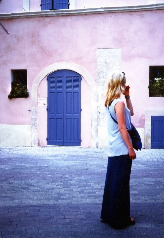 a woman walking on a sidewalk near a pink building