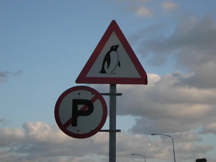 the two signs have a penguin and a stop sign