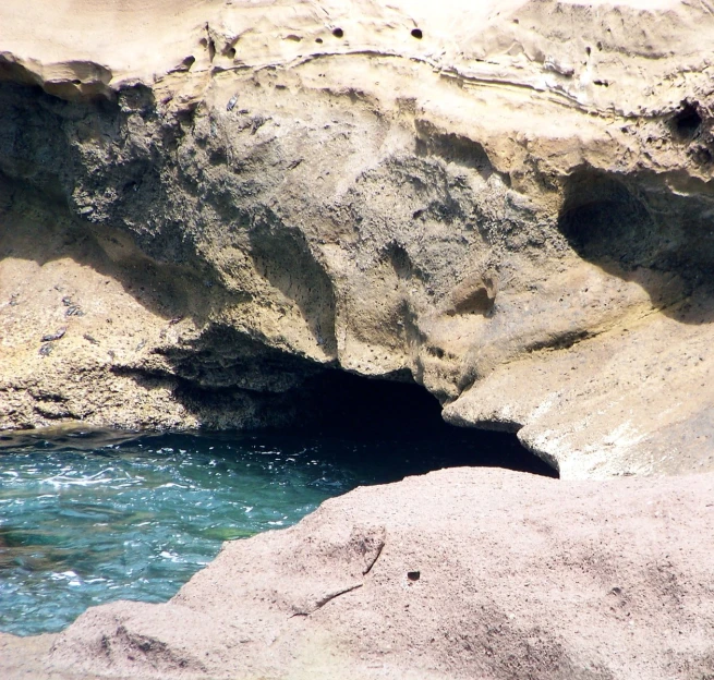 a hole in the rocks on the side of the water