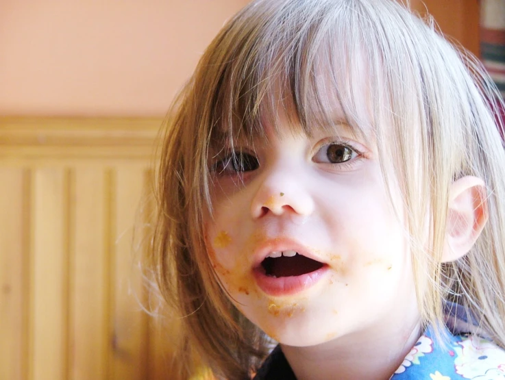 a blonde child with a messy face is eating soing on her face