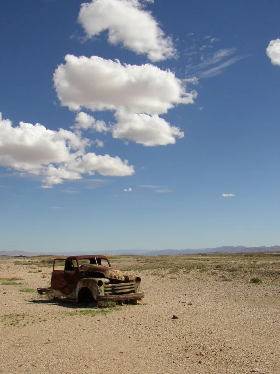 an old truck that is parked in the dirt