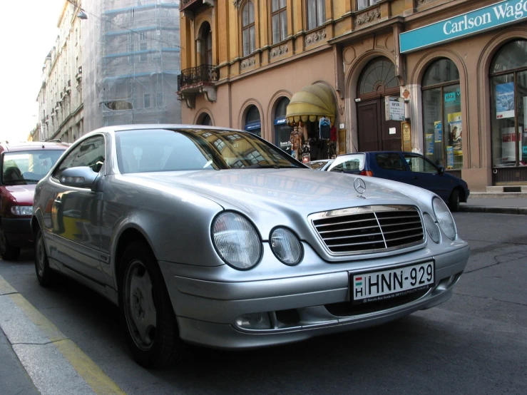 a large mercedes parked on a side walk near cars