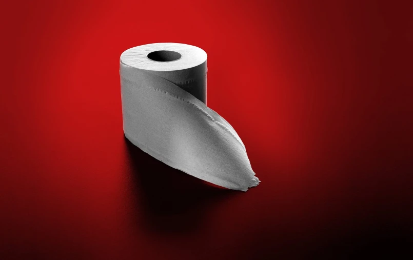 a roll of toilet paper that is on a red surface