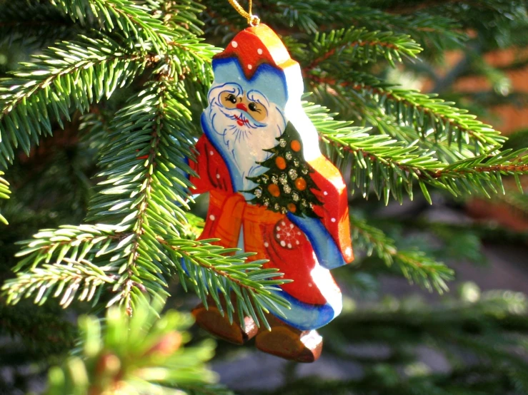 a santa clause ornament hangs from a christmas tree