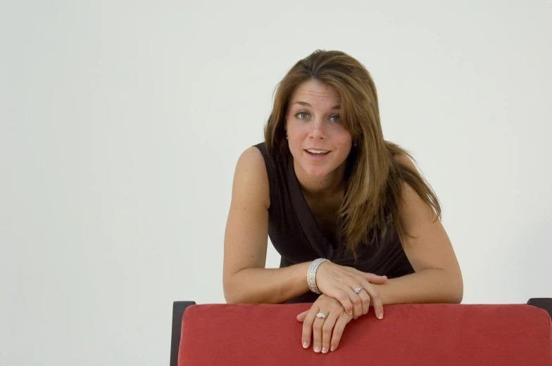 a woman is posing with her red couch