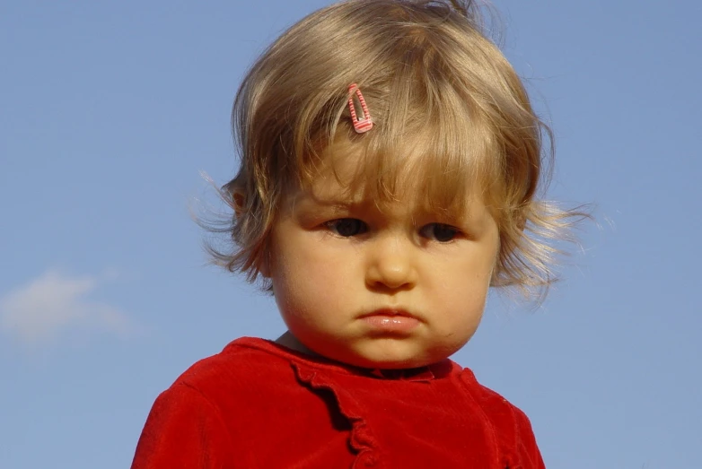 a young blonde boy in a red shirt looking at the camera