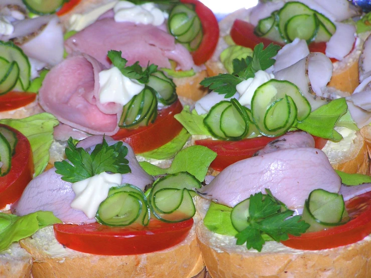 a plate full of sliced up sandwiches with cheese and meat