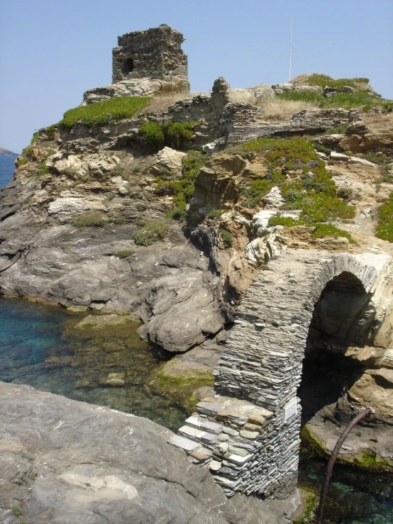 an old bridge made of cement between two rocky shorelines