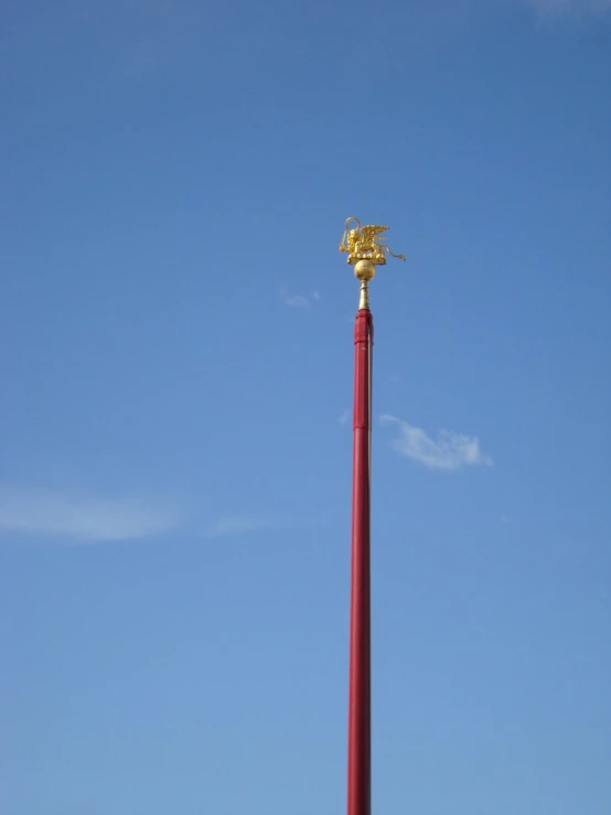 a red pole with a golden statue on top of it