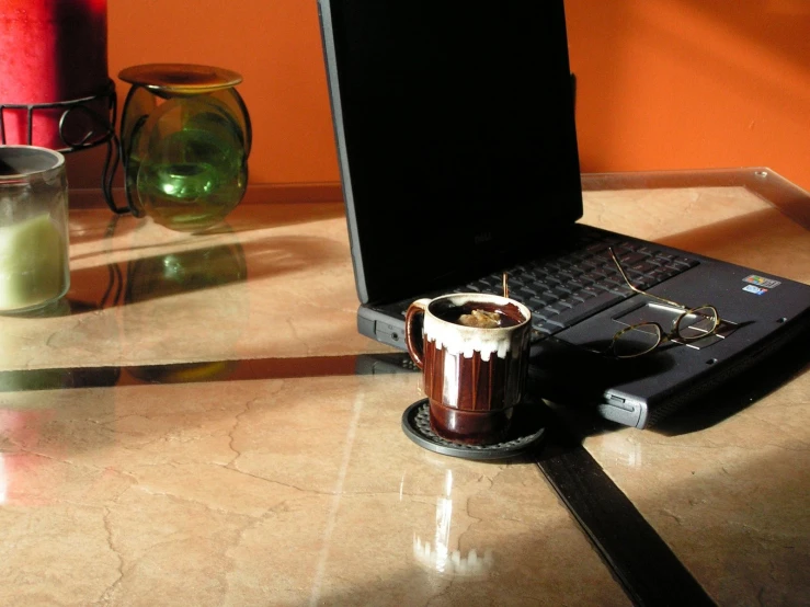 a drink in a plastic cup sits beside a laptop