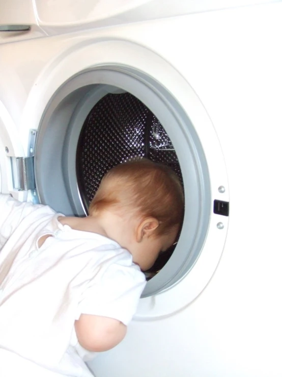 a baby looks down into a white dryer