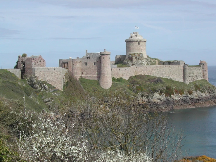 a castle next to water with sea in the background