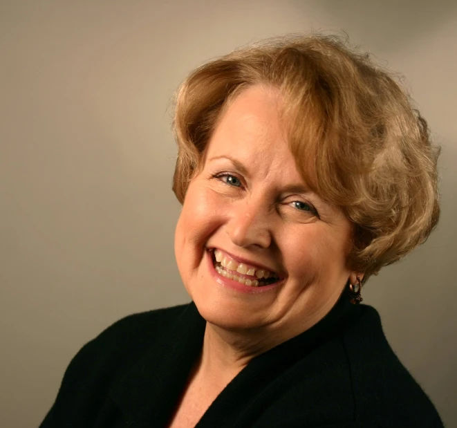 a woman in black jacket smiling and looking at camera