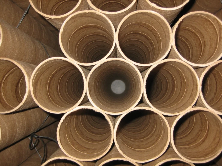 many round and square brown pipes stacked up in a factory