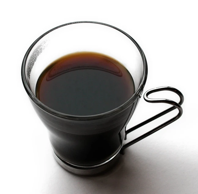 a black cup filled with liquid on a white surface