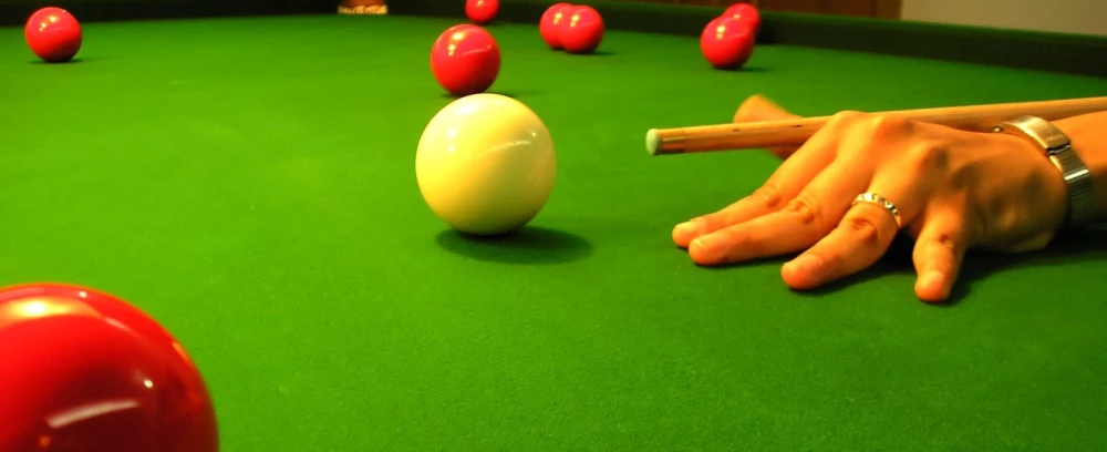 person reaching for ball on pool table with eight - sided ball on the green