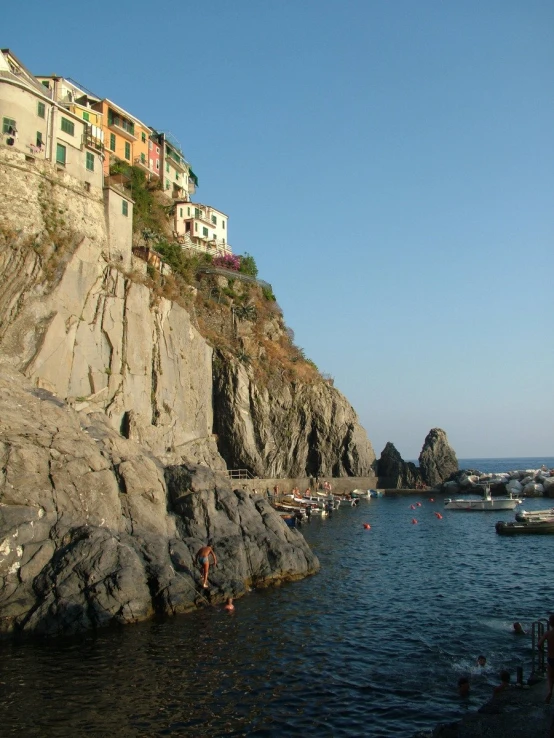 boats floating on top of the water next to a rocky cliff