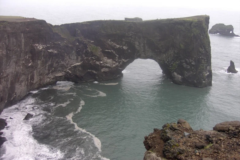 a large arch shaped rock bridge spanning the ocean