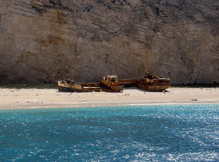 two wooden boats sitting in the sand at a beach