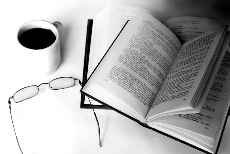 a coffee cup with glasses and an open book