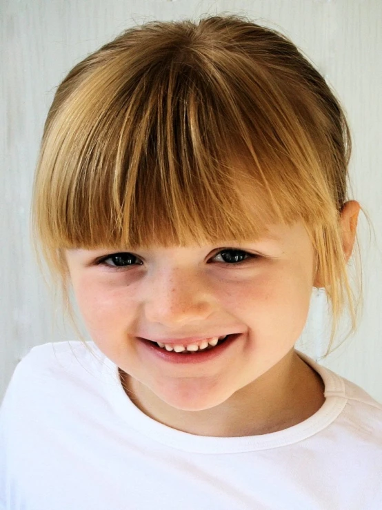 a young child smiling with a hair dryer in front of her