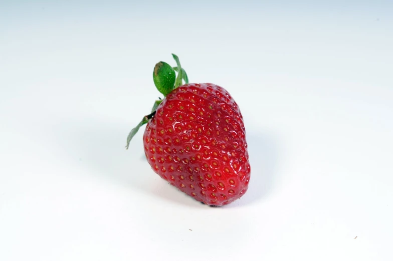 a single strawberry is sitting on a white surface