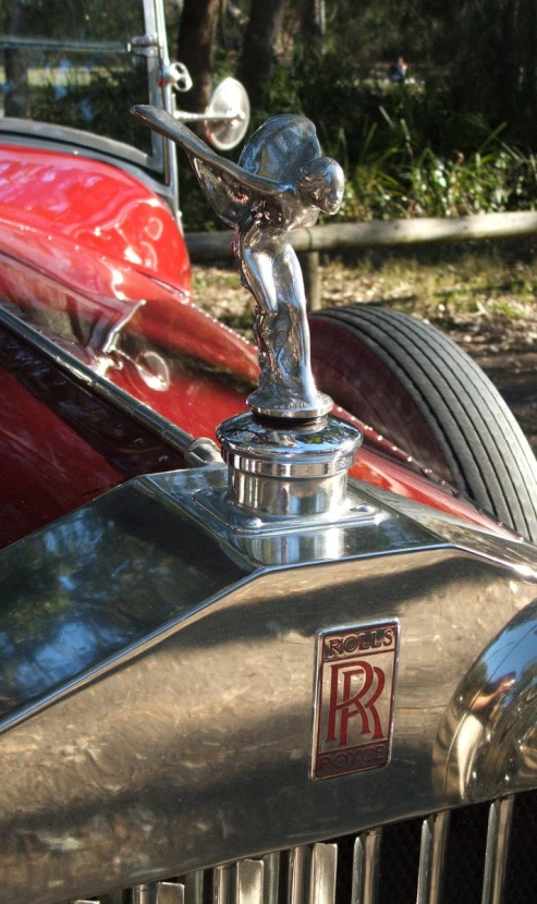 an antique red car with emblem, hood ornament
